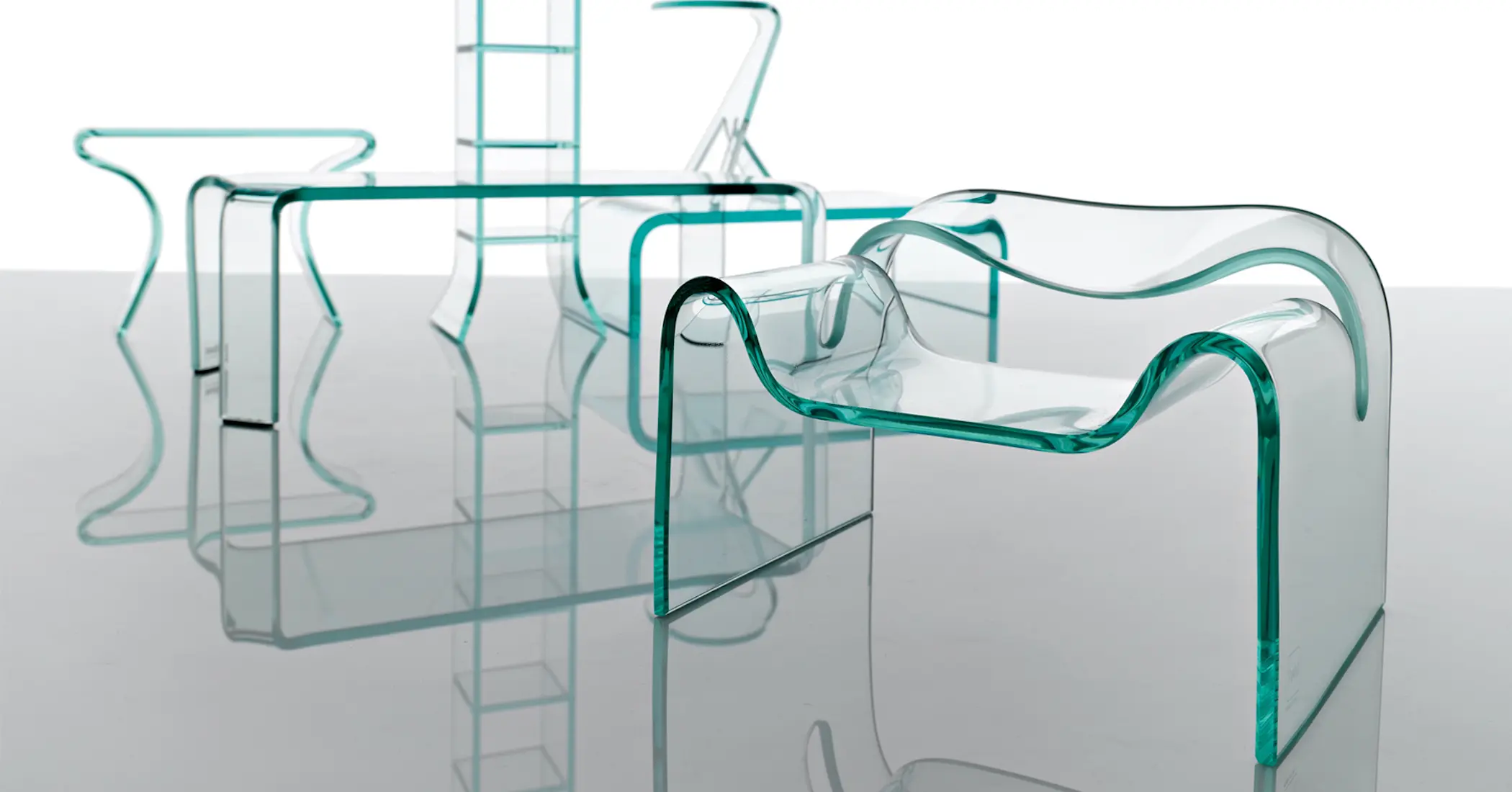 Fiam curved glass chair, table and stool showcasing transparent glass furniture design