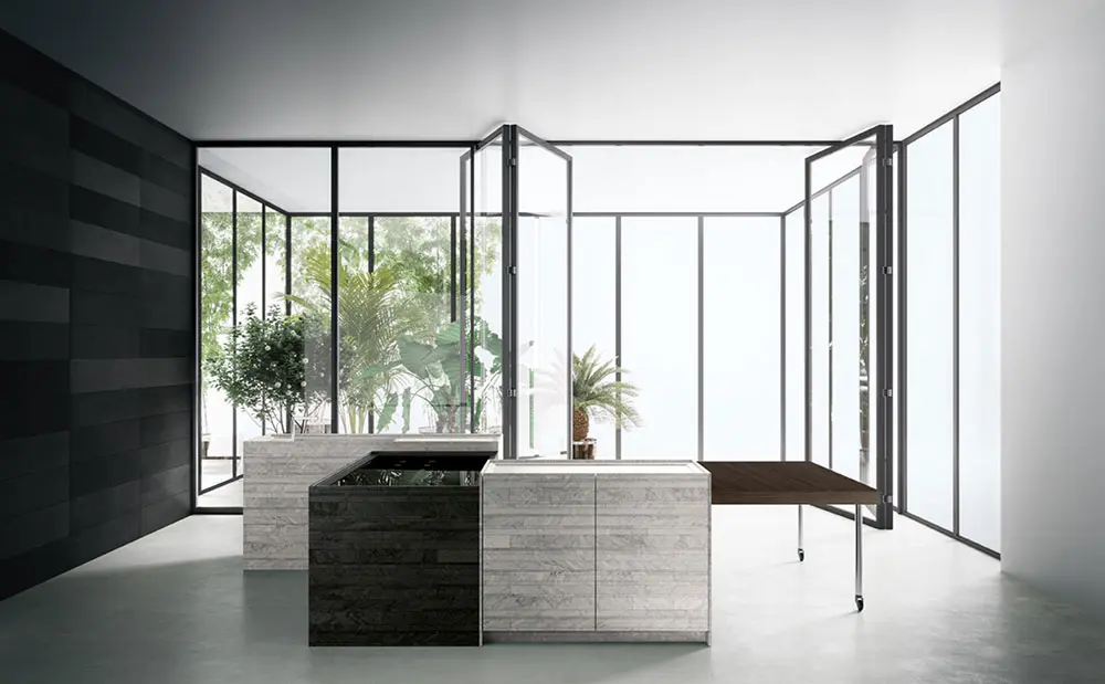 Glass-walled indoor conservatory with stone-clad kitchen islands and potted plants