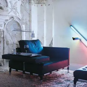 Ornate ruined interior with a dark blue tufted sofa and neon light tubes on the wall