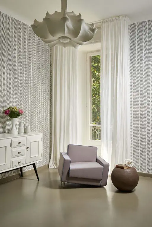 Living room corner with grey armchair, curtained window and scalloped pendant light