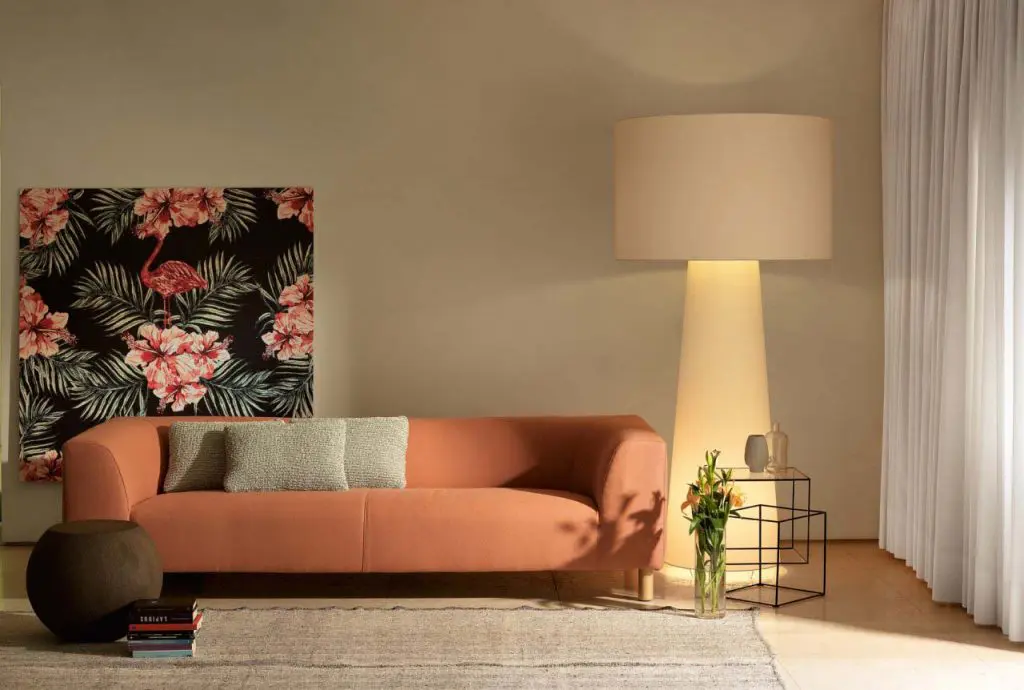Living room with terracotta sofa, floral flamingo artwork and a tall cone-shaped floor lamp