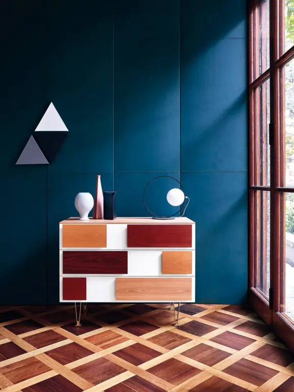 Molteni sideboard with multicolor wood drawer fronts against a dark teal panelled wall