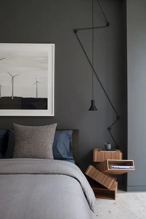Bedroom with grey bedding, textured pillows, wind turbine artwork and a wood nightstand cube
