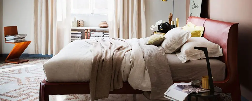 Cassina bedroom with a red leather sleigh bed, linen bedding and a terrazzo floor