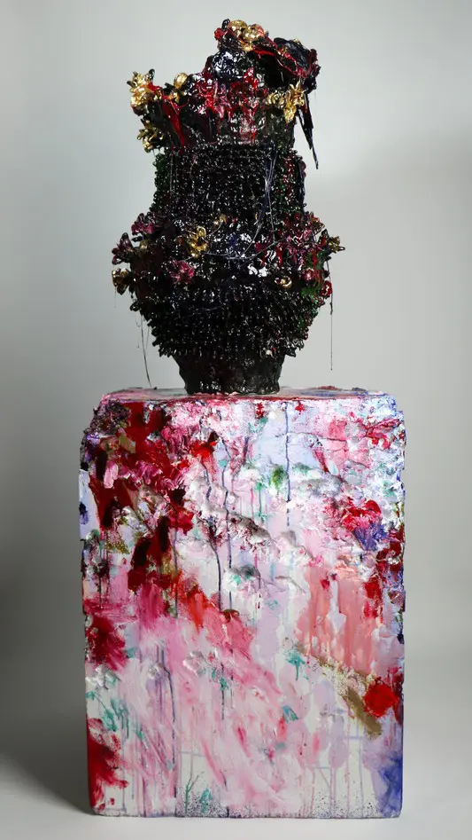 black vase covered in red, purple, blue, and yellow paint and resin