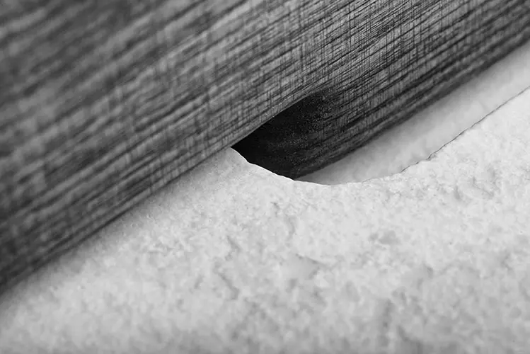 close-up of a wood-textured cabinet edge against a plush white surface