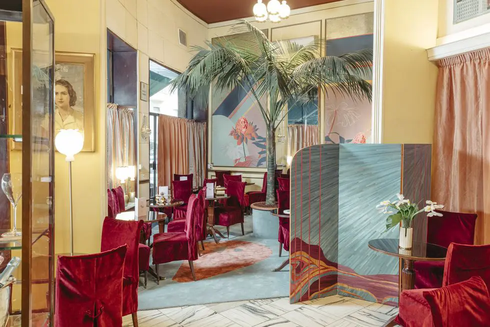 Vintage cafe interior with red velvet chairs, a palm tree and art deco mirrors