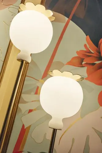 Pair of round frosted glass wall sconces against floral wallpaper