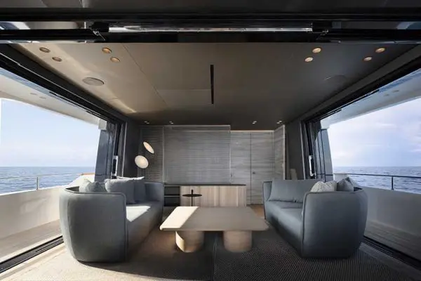 Yacht saloon with gray upholstered sofas facing large windows over open water