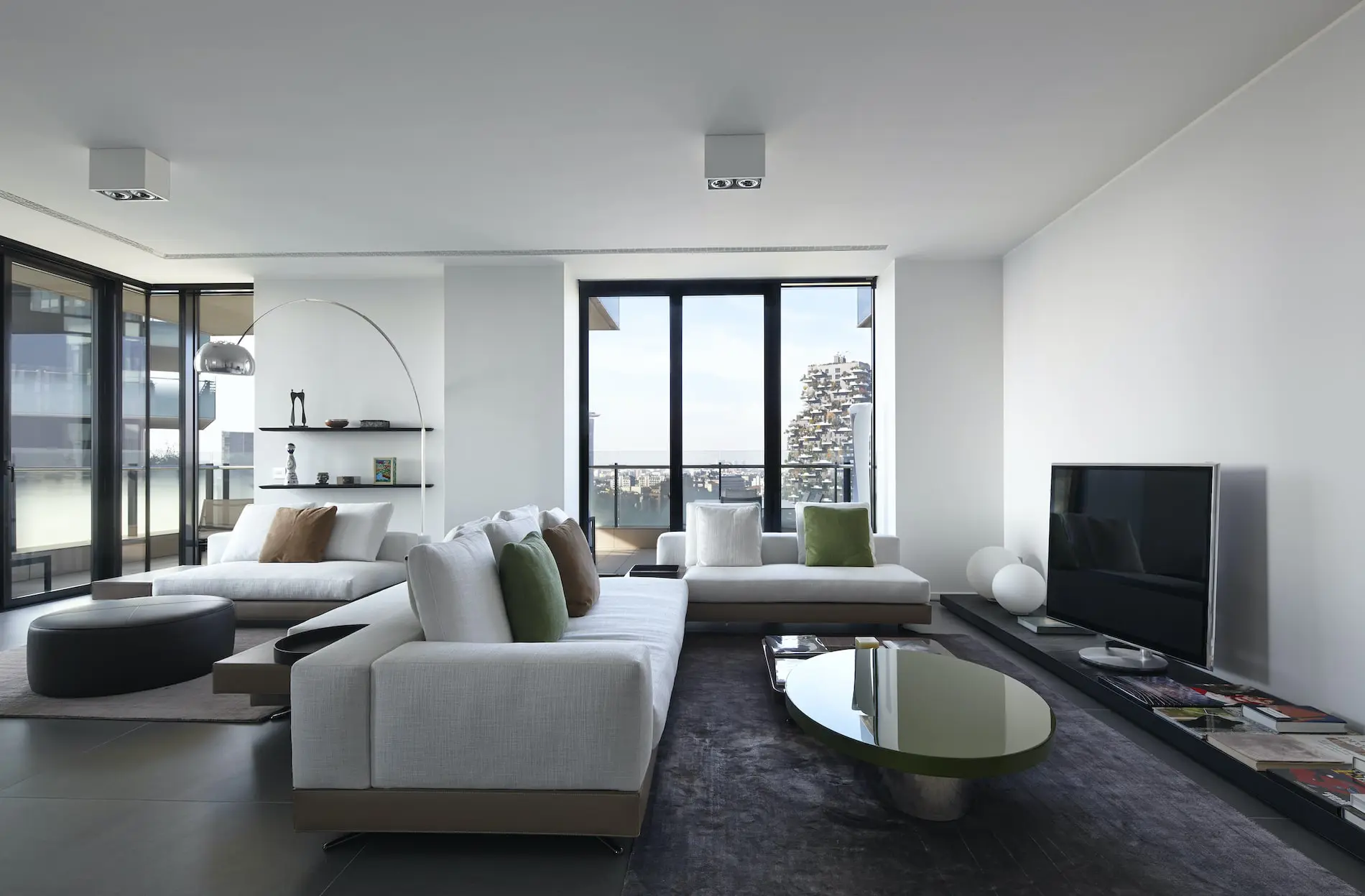 Modern living room with white sofas, green cushions and floor-to-ceiling windows