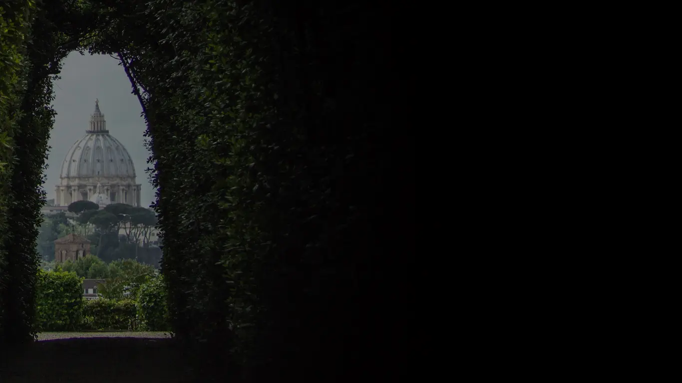 Distant dome of St Peter's Basilica framed through a trimmed hedge archway