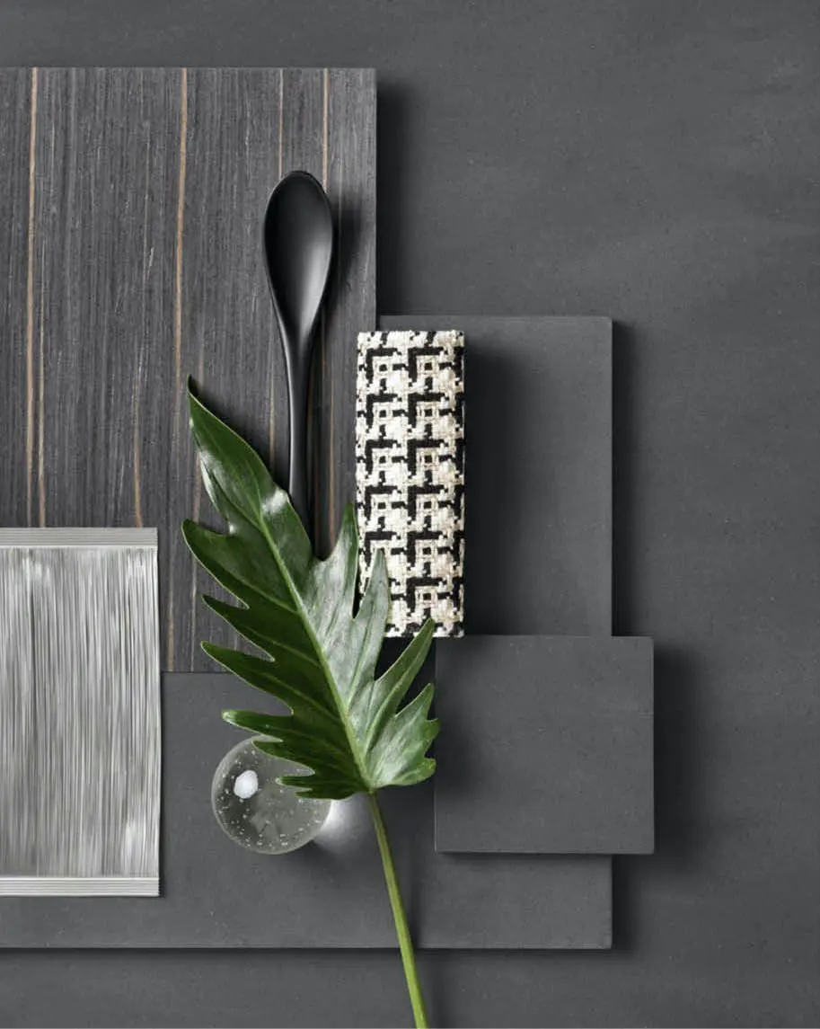 Moodboard with dark wood, brushed metal and houndstooth fabric samples and a tropical leaf