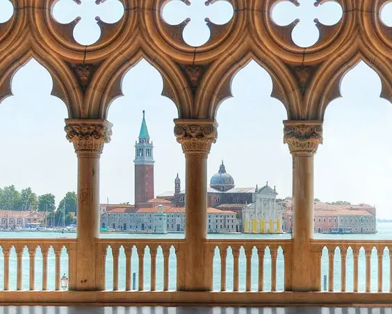View through Gothic arched columns of a domed church across the water in Venice