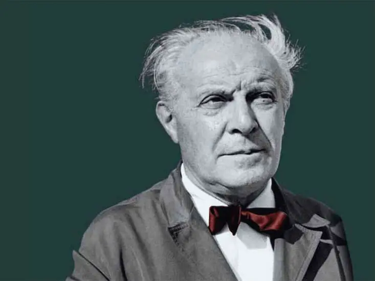 Black-and-white portrait of an elderly man with a red bow tie on a green background