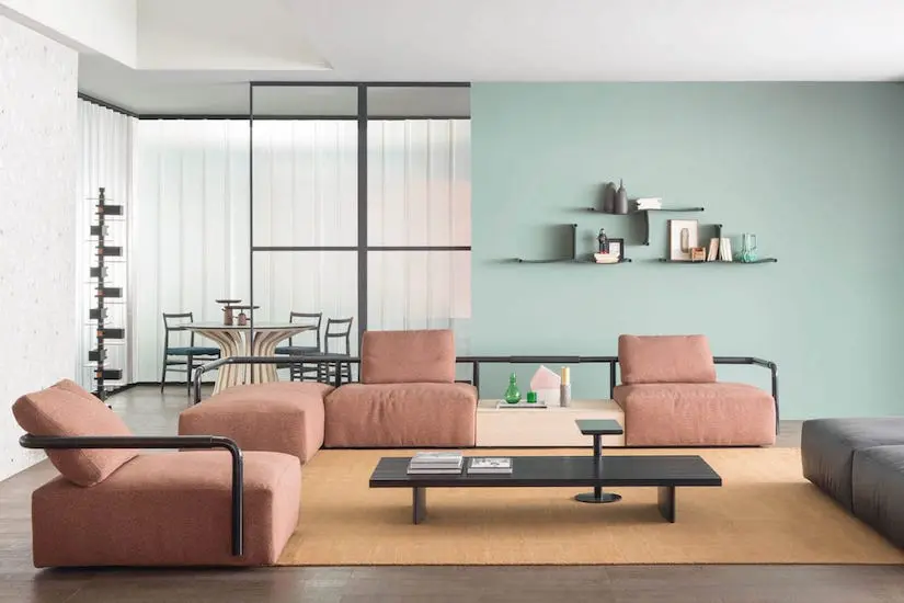 Living room with pink modular sofas, a low black coffee table and a mint green wall