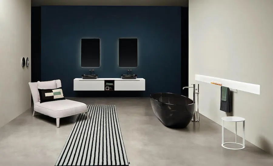 Bathroom with a black oval freestanding tub, white floating double vanity and a navy blue wall