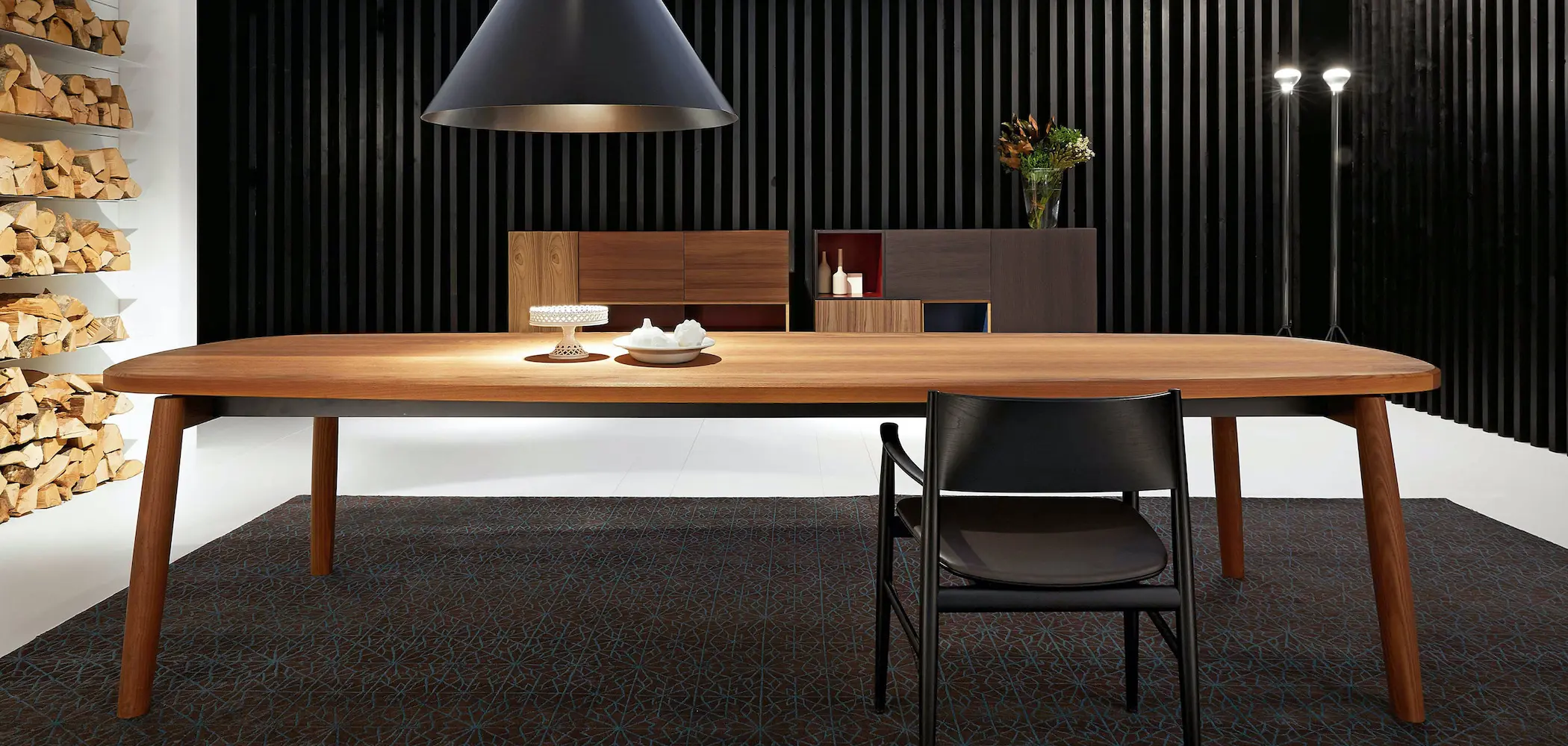 Porro wooden oval dining table with black leather chair and wall-mounted storage sideboard
