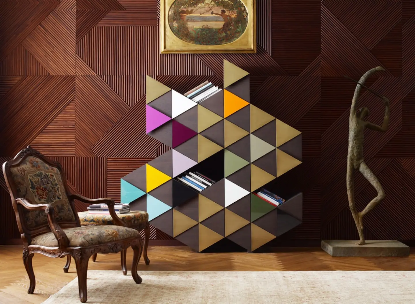 Emmemobili Arlequin bookcase of coloured triangular modules against a patterned wood wall