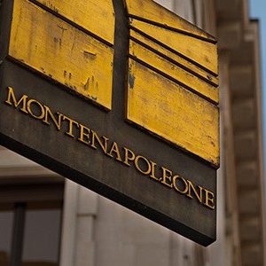 Street sign for via Montenapoleone in Milan with a blue sky behind the sign