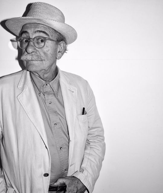 portrait in black and white of ugo la pietra an older man wearing glasses, a hat, and a mustache