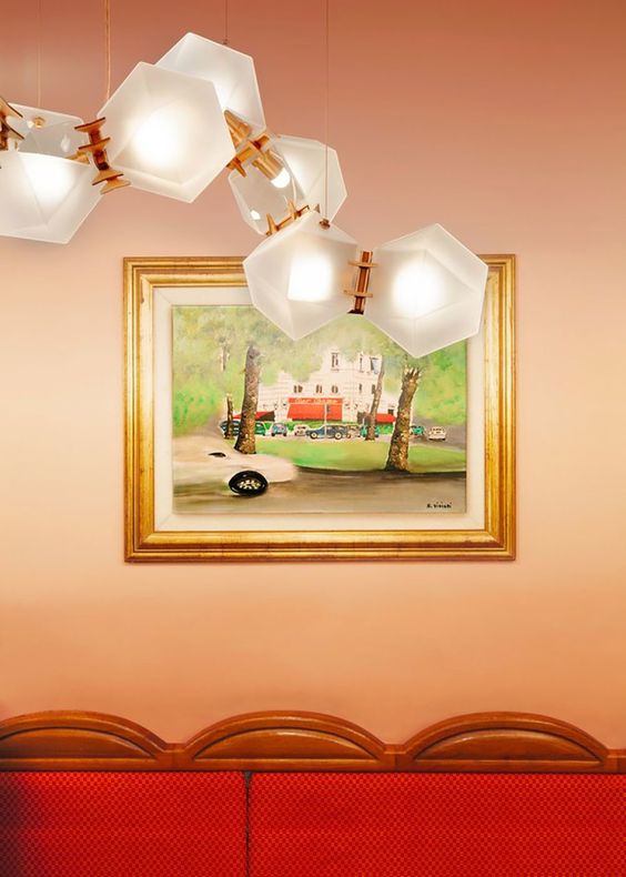 red sofa with framed art on wall and geometric lighting feature on pink wall