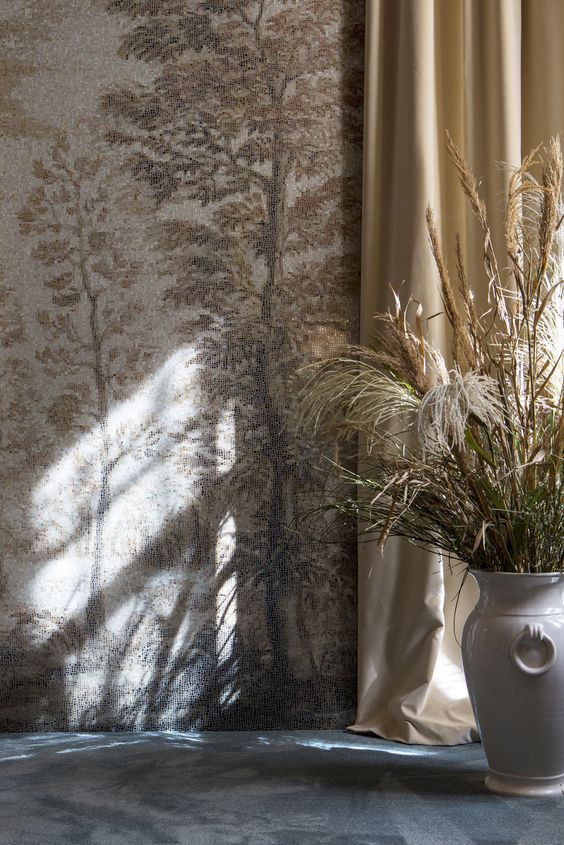 blue carpet with a white vase holding wild grasses with a wall mosaic of tiny glass tiles of a scene of trees