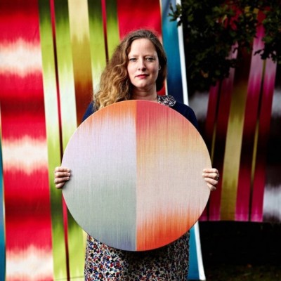 portrait of a woman with red hair holding a round artwork