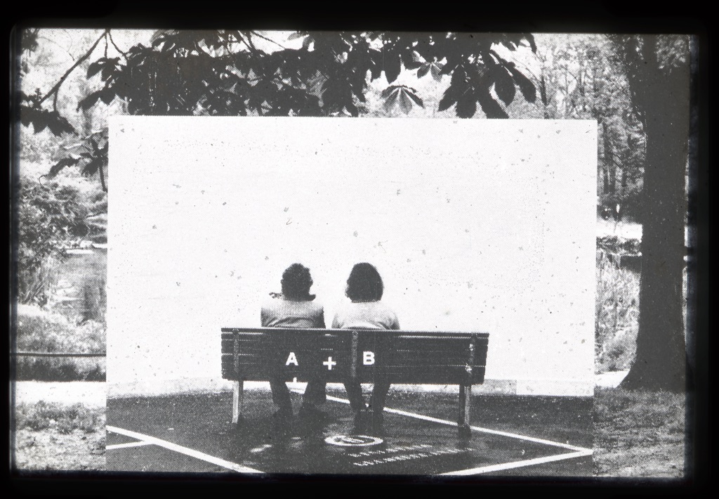 photograph of two people sitting on a bench